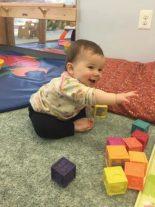 A baby reaching for wooden blocks